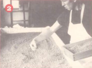 worker sprinkling ingredients into a vat