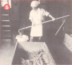 Worker scooping mixture out of a bucket into a trough