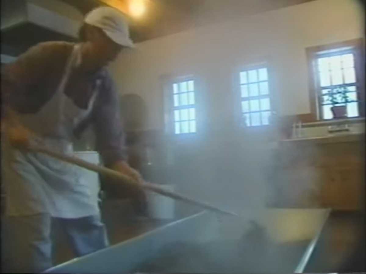 worker stirring a vat in a steamy miso kitchen