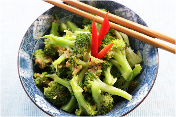 broccoli in a blue bowl with chopsticks