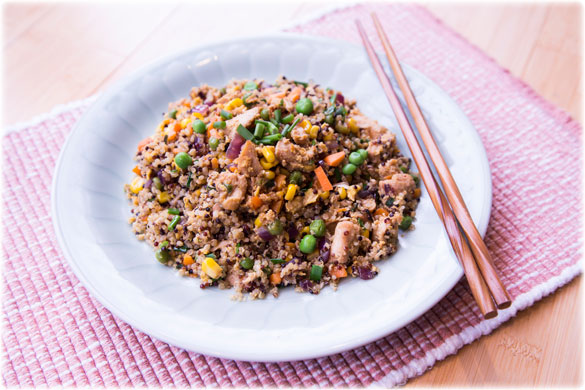 chicken fried quinoa on a white plate with chopsticks