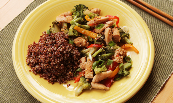 quinoa with chicken vegetable stir fry on a yellow plate