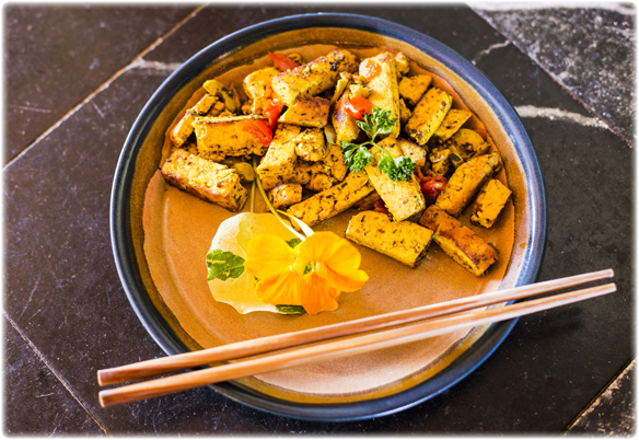 stir-fried tofu on a plate with chopsticks